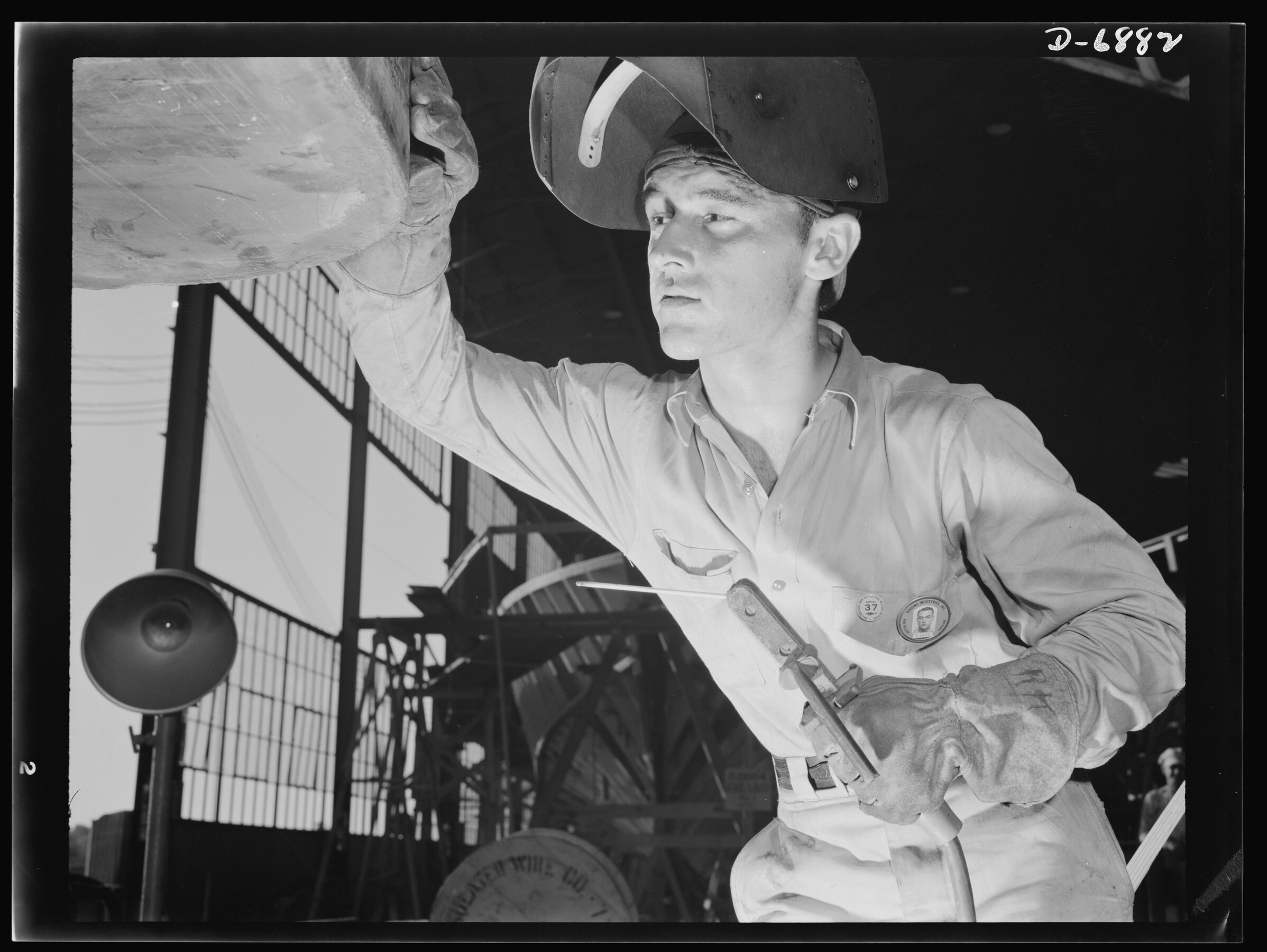 An electric-arc welder at Higgins Industries examines a fresh bead on a steel ramp boat in July 1942.